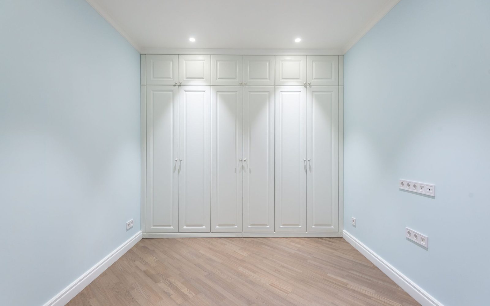 Painted built-in wardrobes fitted across a bedroom wall